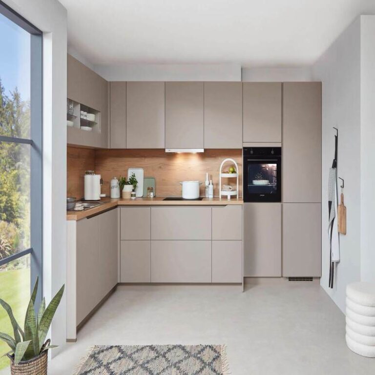 Musterküche in Kaschmir Musterküche in Kaschmir als L-Küche mit Holzrückwand und Backofen im Hochschrank – Küchenaufbau Moers